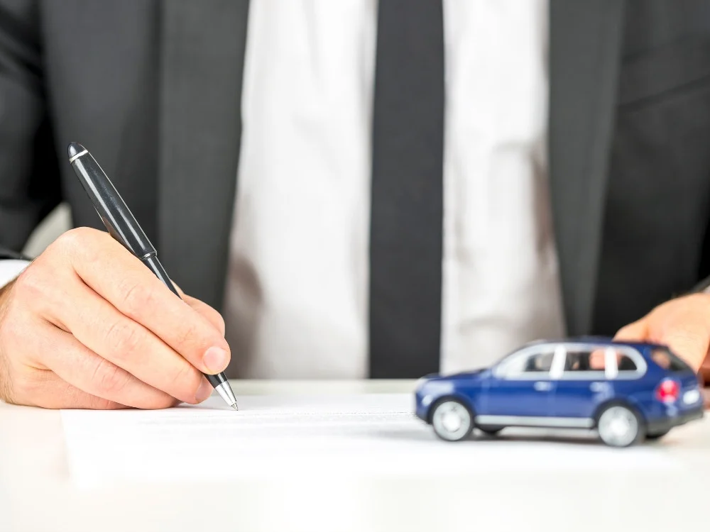 Firma de documentación de un vehículo junto a un coche en miniatura
